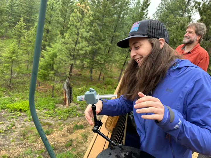 Researcher setting up a feeder on an outdoor flight arena in the Montana pines
