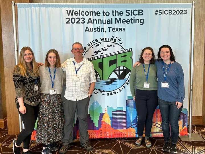 Kendra Wisenbaker, Emily Blackwell, Don Powers, Emma Ortiz and Whitney Dobbyn in front of the SICB 2023 Austin welcome banner